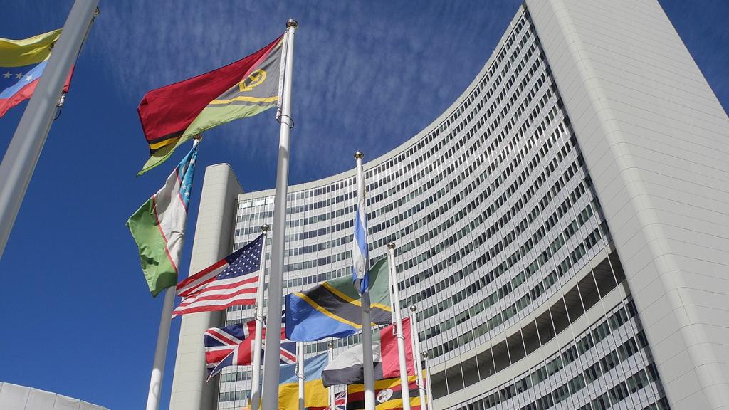 Photo Credit: (Cover Photo Above) The IAEA headquarters with member flags in Vienna. Creative Commons License. Photo from 2022 by Schölla Schwarz. 
